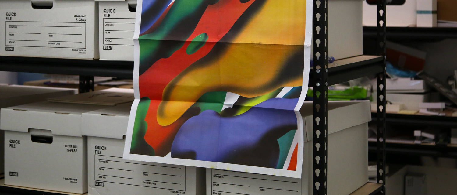 Multicolor art print hanging on a shelf in front of multiple file boxes. 